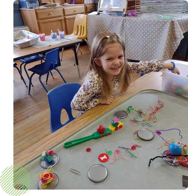 A little girl sitting at the table playing with toys.