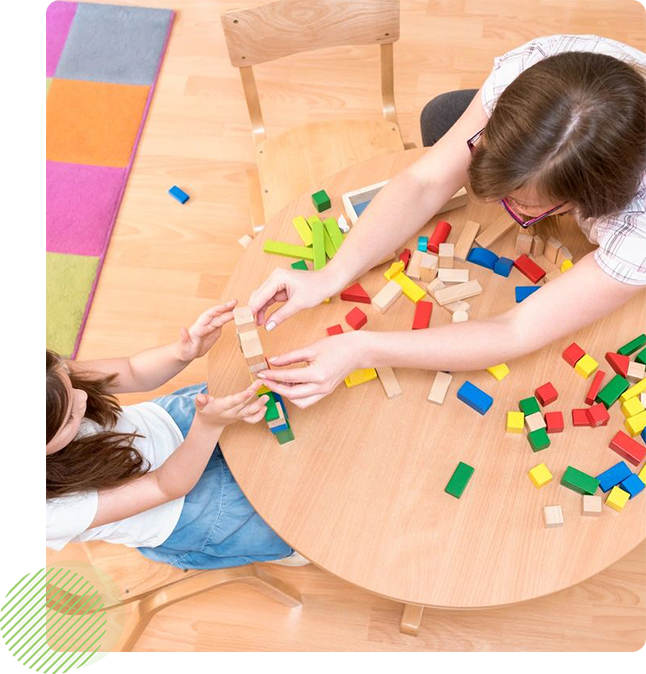 Two children playing with blocks on a table.