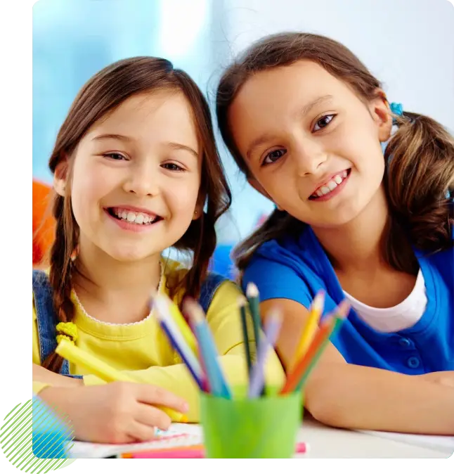 Two girls sitting at a table with pencils.