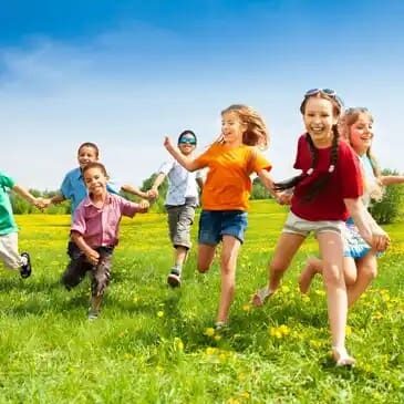 A group of children running in the grass.